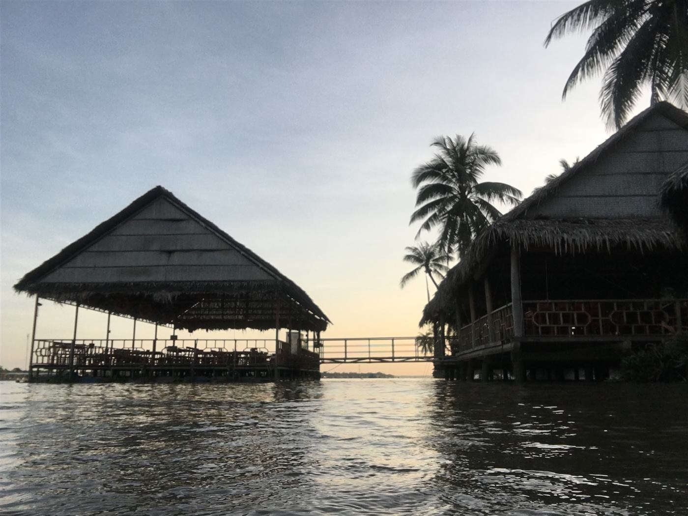 Chòi lá và cầu nối bên sông lúc hoàng hôn